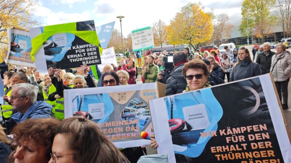 Blick in die Menschenmenge bei der Demo "Erhalt der Thüringer Bäder" in Erfurt im Oktober 2025, bei der viele verschiedene Personen ihre Demo-Schilder in die Kamera zeigen