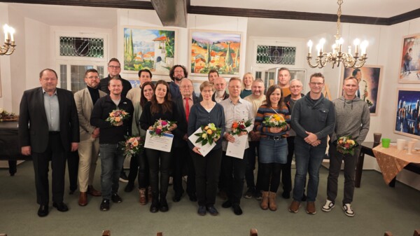 Gruppenbild der Ehrenpreisträger*innen 2025 in der Rathausgalerie mit Urkunden und Blumensträußen in den Händen