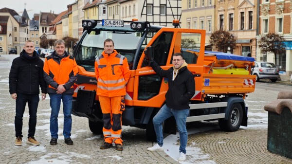 Stellvertretender Bauamtsleiter Etienne Bräutigam, Bauhofsleiter Mario Spranger, Stellvertretender Bauhofsleiter Sebastian Ahner, Bürgermeister Sven Schrade vor dem neuen orangefarbenen Multicar des Bauhofes