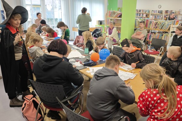 Faschingsbasteln 2026 in der Bibliothek Blick auf die bastelnden Kinder und Eltern an einer langen Tafel in der Kinderabteilung der Schmöllner Bibliothek beim Faschingsbasteln