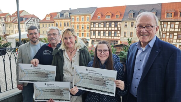 Die Vertreter*innen von Kita, Rathaus und Verein präsentieren stolz die Schecks für die drei schönsten Schaukästen des Schmöllner Bahnhofes auf der Treppe vor dem Rathaus 