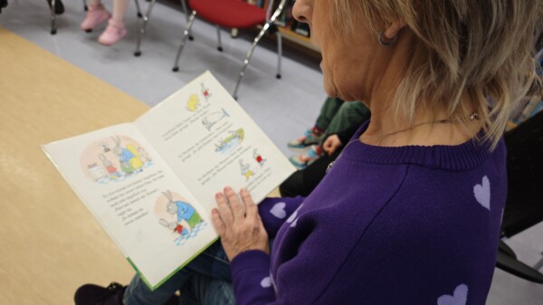 Bibliothekarin liest aus Buch vor.