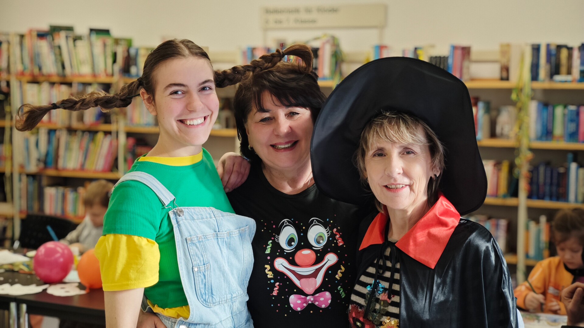 Das Bibliotheksteam im Kostüm Gruppenbild des Bibliothekteams mit der Bundesfreiwilligen Lilly Östreich als Pippi Langstrumpf, der Ehrenamtlichen Elke Koch in lustigem T-Shirt und der Bibliothekarin Heike Milke als Hexe beim Faschingsbasteln in der Bibliothek