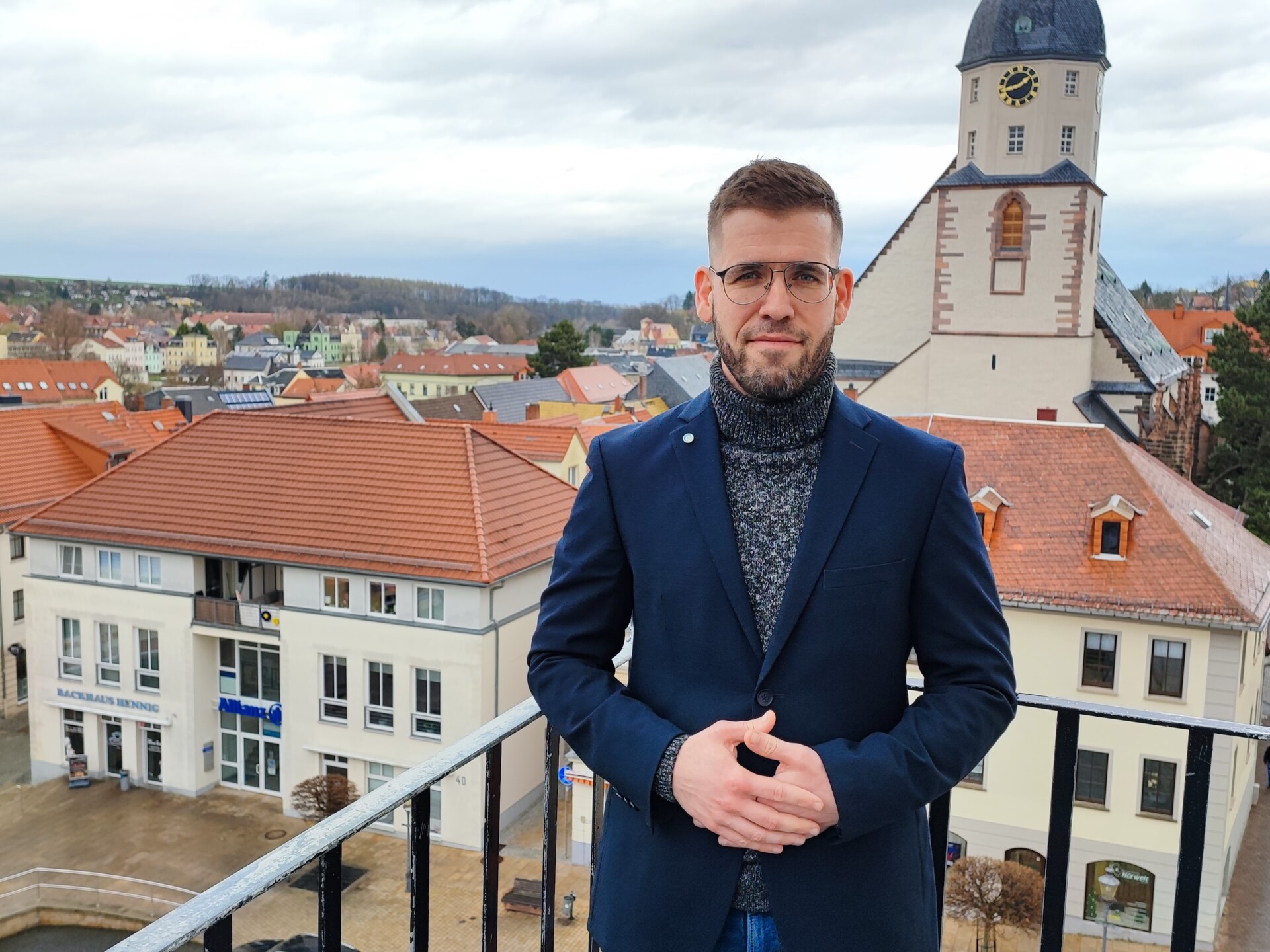 Bürgermeister Sven Schrade auf dem Rathausturm, Stadtkirche im Hintergrund