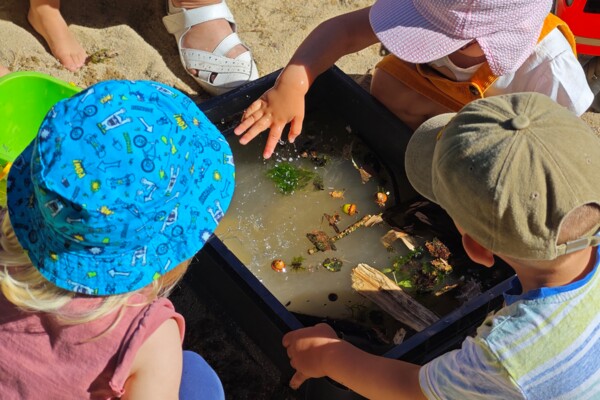 Krippenkinder matschen im Sandkasten Krippenkinder matschen im Sandkasten