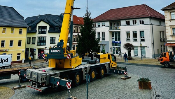 Blick vom Haupteingang des Rathauses auf den Marktplatz, auf dem mithilfe eines Kran-Fahrzeuges der Weihnachtsbaum abgestellt wird