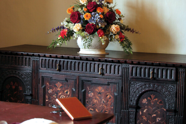 Zu sehen ist ein Blumenstrauß auf einem Sideboard.